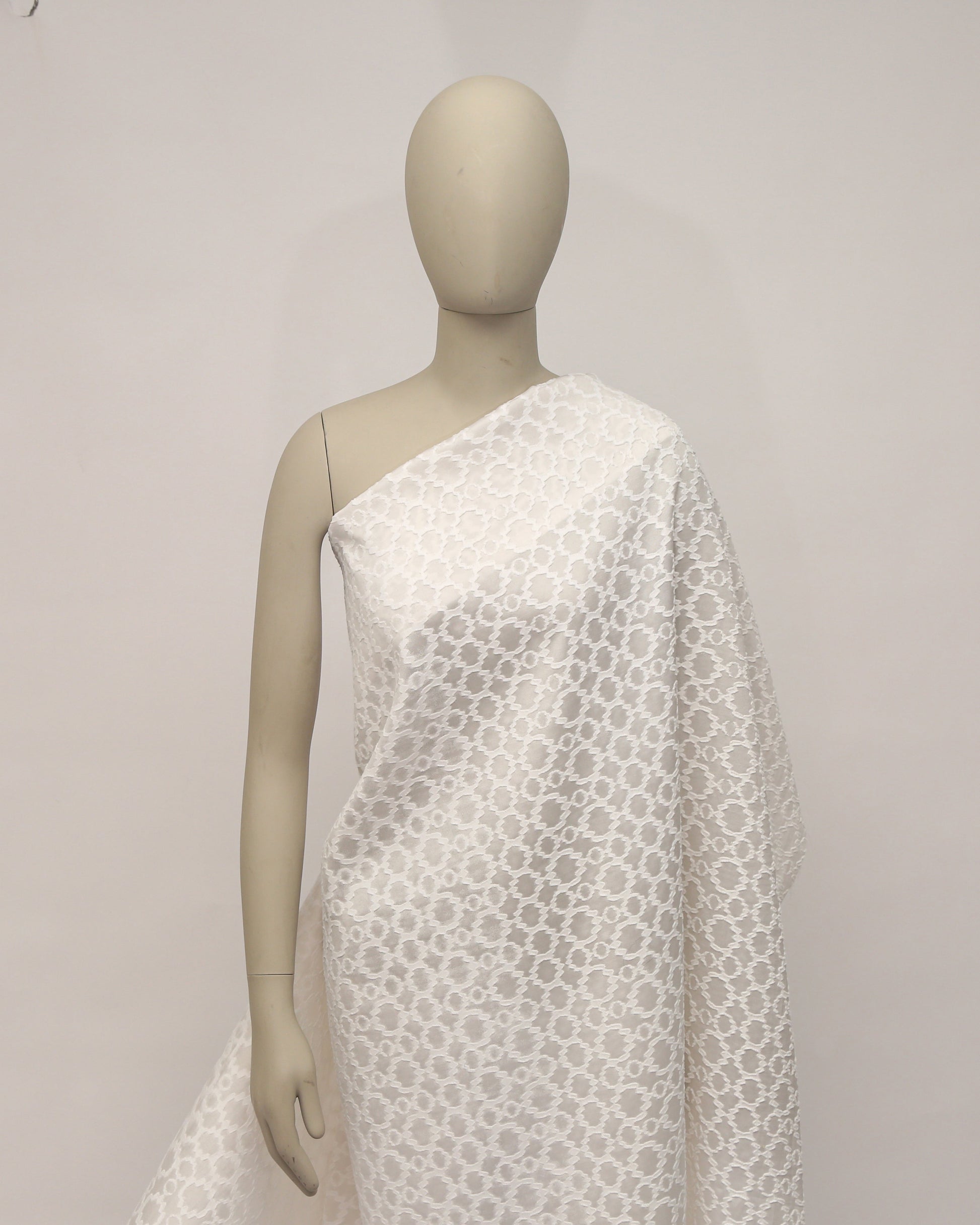 Mannequin wearing a white textured dress against a plain background