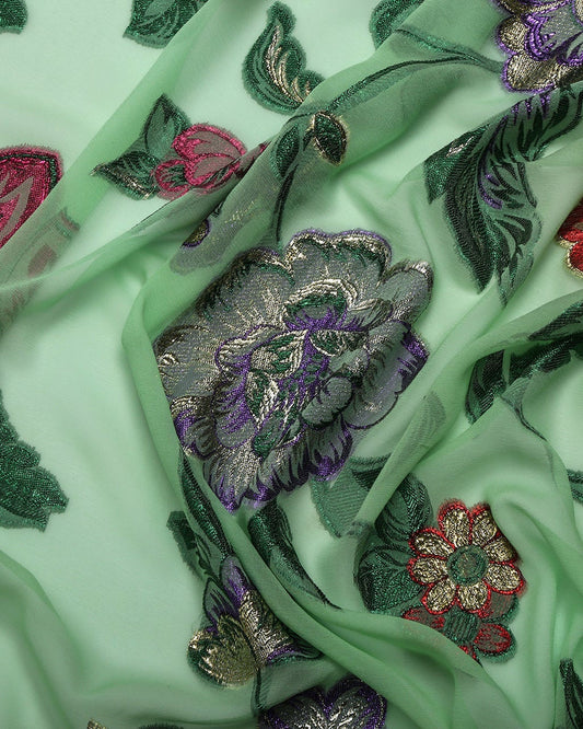 Close-up of embroidered fabric with floral patterns on a light green background