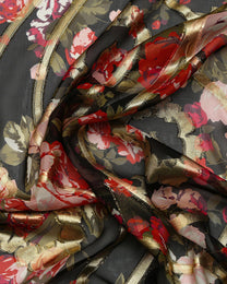 Close-up of floral fabric with red, pink, and gold colors on a dark background