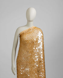 Mannequin wearing a gold sequin dress against a gray background